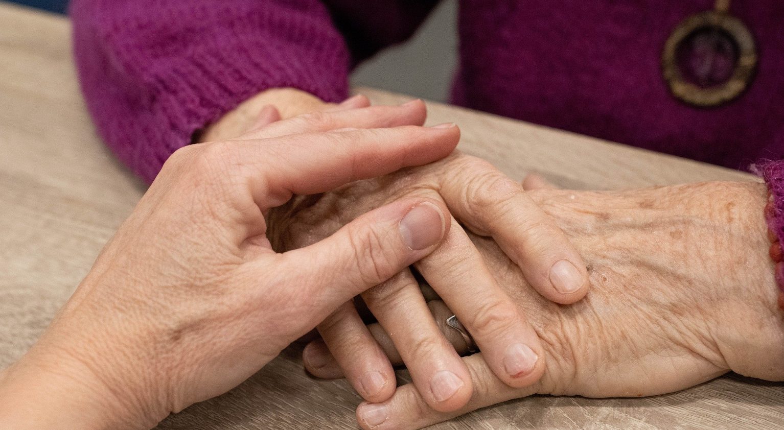 Person holding hand of elderly woman