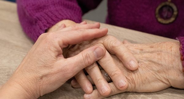 Person holding hand of elderly woman