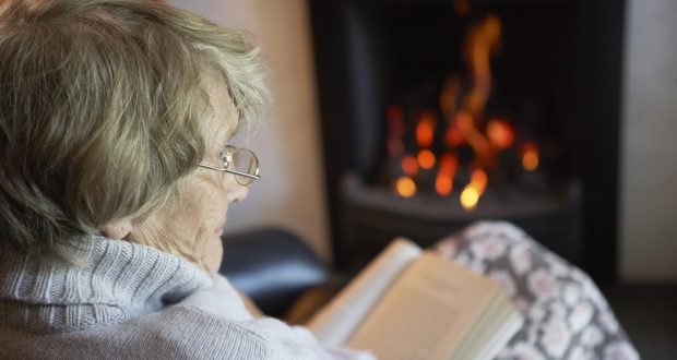 Older lady sat by the fire with a blanket