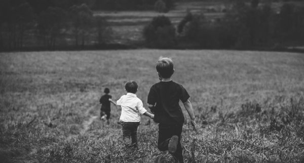 3 Small children running down a field together