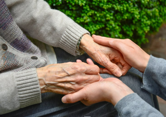An elderly person holding hands with a younger person