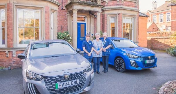 Three people stood outside Beaumond House with two cars side by side
