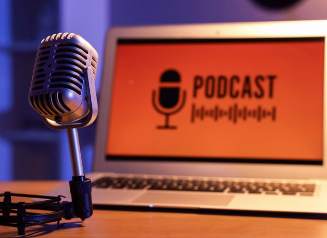 Photo of a microphone and a laptop with the word podcast on it